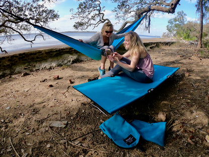 Two people using a blue GO-KOT outdoors near a beach.